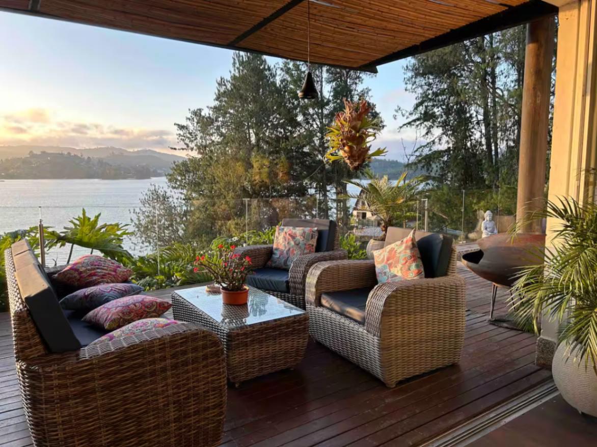 Terraza de villa de lujo con muebles de mimbre y vista panorámica al lago en Peñol Guatapé